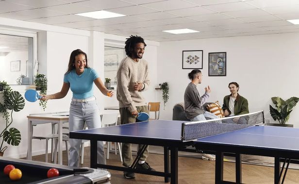 Students gather around a ping pong table as one prepares to serve