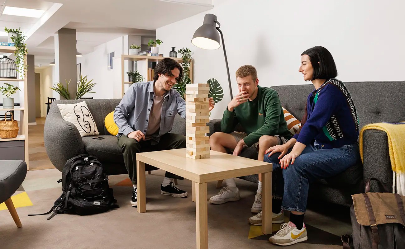 A group of students sit around a table, a game of jenga is set up on top