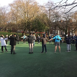 Group stood in a circle with arms outstretched to hold each others hands
