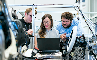 Group of engineers around equipment and a computer