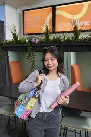 Vietnamese girl stood with her bag and book smiling