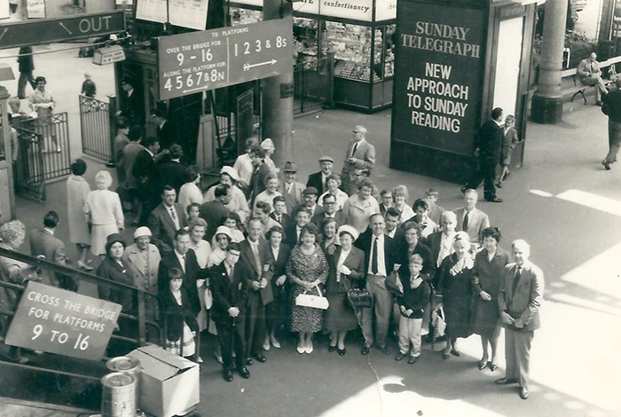 An old black and white photo showing a large group of Firth's Carpets workers gathered at a railway platform waiting for a train to go on a day out