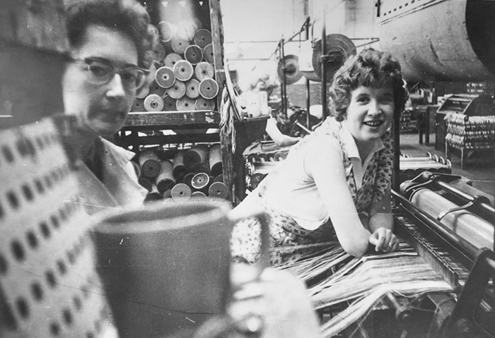 An old black and white photo showing Lisa Taylor's mum Nancie (left) with a colleague posing for the camera whilst working with carpets at Clifton Mill